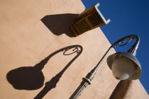 Street lamp and gutter detail with shadows on adobe style building