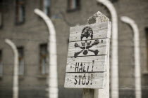 Detail of a sign in the concentration camp. Black scull and crossbones on white painted wood with a warning written underneath.Eastern EuropeNazisCrueltyHolacaustPersecutionDeath