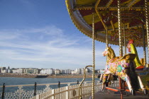 Empty fairground carrousel on Brighton Pier with the City and beach in the distance