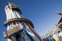 The Helter Skelter ride on Brighton Pier with tourists walking past and the city in the distance