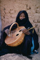 Tuareg woman playing an Imzad.  Traditional instrument consisting of a goatskin covered gourd or wooden resonator played with a curved bow and horsehair string.inzad Nomadic muslim minority of Berbe...