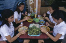 Group of schoolgirls eating lunch at street stall.