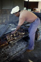Man cooking jerk pork over an open fire