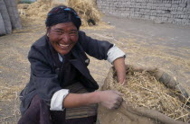 Smiling farm worker with bag of straw.