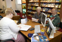 Male and female customer in a Travel Agents office discussing their holiday arrangements with a female travel consultantEuropean Great Britain Northern Europe UK United Kingdom British Isles
