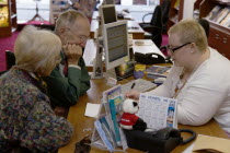 Male and female customer in a Travel Agents office discussing their holiday arrangements with a female travel consultantEuropean Great Britain Northern Europe UK United Kingdom British Isles