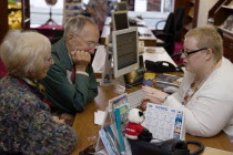 Male and female customer in a Travel Agents office discussing their holiday arrangements with a female travel consultantEuropean Great Britain Northern Europe UK United Kingdom British Isles