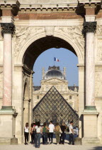 People walking from the Jardin des Tuileries through the Arc de Triomphe du Carrousel towards the pyramid entrance to the Musee du LouvreFrench Western Europe European