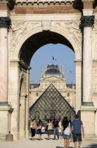 People walking from the Jardin des Tuileries through the Arc de Triomphe du Carrousel towards the pyramid entrance to the Musee du LouvreFrench Western Europe European