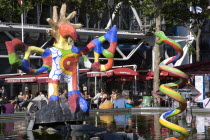 People sitting at tables under umbrellas beside the colourful contemporary fountains by Niki de Saint Phalle and Jean Tinguely in Place Igor Stravinsky beside the Pompidou Centre in Beauborg Les Halle...