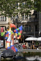 People sitting at tables under umbrellas beside the colourful contemporary fountains by Niki de Saint Phalle and Jean Tinguely in Place Igor Stravinsky beside the Pompidou Centre in Beauborg Les Halle...