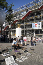 Tourists watching a street performer in the square outside the Pompidou Centre in Beauborg Les Halles with artists selling their work on the pavement in the foregroundFrench Western Europe European