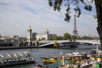 Houseboat barges moored at the Port des Champs Elysees on the River Seine with the Pont Alexandre III bridge and the Eiffel Tower beyondFrench Western Europe European