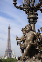 Ornate bronze lamp-post with cherubs on the Pont Alexandre III bridge across the River Seine with the Eiffel Tower in the distanceFrench Western Europe European