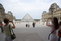 Tourists taking digital photographs of the pyramid entrance of the Louvre MuseumFrench Western Europe European