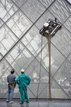 Workmen watching robot window cleaning machine on the pyramid at the Louvre MuseumFrench Western Europe European