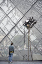 Workman watching robot window cleaning machine on the pyramid at the Louvre MuseumFrench Western Europe European