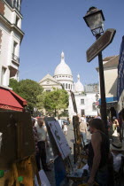 Montmartre Tourists walking past artists painting in Place du Tertre square beside the Church of Sacre CouerFrench Western Europe European