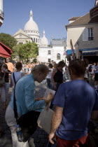 Montmartre Place du Tertre a square beside the church of Sacre Couer with a tourist discussing a painting with an artist vendorFrench Western Europe European