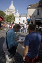 Montmartre Place du Tertre a square beside the church of Sacre Couer with a tourist discussing a painting with an artist vendorFrench Western Europe European