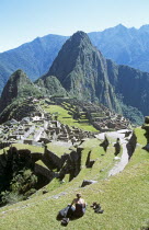 Inca ruins  terraces  visitor sitting on terrace  and Huayna Picchu.Cuzco TravelTourismHolidayVacationExploreRecreationLeisureSightseeingTouristAttractionTourDestinationMachuPicchuMachu...