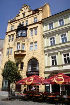 Old Town. Tourists sitting at tables under umbrellas outside a cafe with a painted facade in Ovocny trh  the fruit marketPraha Ceska Eastern Europe European Bar Bistro Restaurant