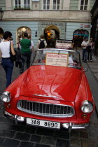 Tourists walking past a red Skoda  parked in the street  used for sightseeing tours of the Old TownPraha Ceska Eastern Europe European
