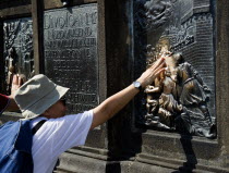 Tourist touching for luck the relief of the martyrdom of St John Nepomuk on the Charles BridgePraha Ceska Eastern Europe European Religious