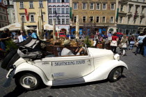 Old Town. Vintage open topped car used for sightseeing tours being driven amongst tourists and past a street cafe in Male Namesti  Male SquarePraha Ceska Eastern Europe European Automobile Automotive...