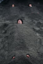 Sunabulo. Hot Sand Bath with men submerged in sand with only heads and feet showing above surfaceAsia Asian Japanese Nihon Nippon