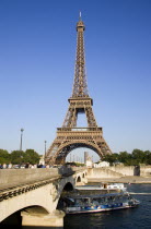 A bateaux Mouches pleasure boat with tourists and a barge pass beneath the Pont dIena bridge with the Eiffel Tower beyondEuropean French Western Europe