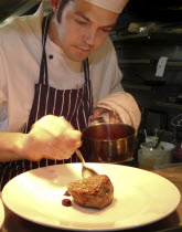 Chef Plating Up Fillet Steak and Raspberry CoulisFood  cooking Great Britain UK United Kingdom British Isles Northern Europe