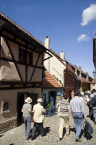Tourists walking along Golden Lane in Prague castle lined with artisan shopsPraha Ceska Eastern Europe European
