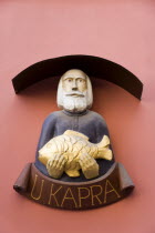 Wall sign in the Old Town of a bearded man holding a golden fish outside a shopPraha Ceska Eastern Europe European Store