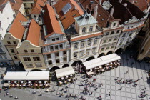 Rooftops and pavement restaurants with diners in the Old Town Square and pedestrians walking pastPraha Ceska Eastern Europe European