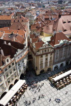 Rooftops and pavement restaurants in the Old Town Square with pedestrians walking pastPraha Ceska Eastern Europe European