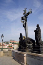 The 17th Century wooden Crucifiction on the Charles Bridge across the Vltava River with Prague Castle and St Vituss Cathedral beyond in HradcanyPraha Ceska Eastern Europe European Religion