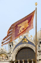 The Venetian flag bearing the winged Lion of St Mark flying in front of St Marks Basilica in Piazza San Marco