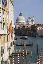 The Grand Canal with vaporetto and gondolas with the Baroque church of Santa Maria della Salute seen from the Academia Bridge next to the Palazzo Franchetti Cavali adorned with flags which belonged to...