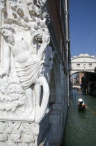 The early 15th Century sculpture The Drunkenness of Noah  symbolic of the frailty of man  on the corner of the Doges Palace with gondolas passing below the Bridge of Sighs beyond