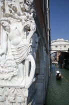 The early 15th Century sculpture The Drunkenness of Noah  symbolic of the frailty of man  on the corner of the Doges Palace with gondolas passing below the Bridge of Sighs beyond