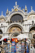 The four bronze Horses of St Mark on the facade of the basilica surrounded by 17th Century mosaics. A stall in the Piazza San Marco in the foreground sells souvenirs