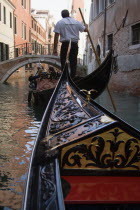 The bow of a gondola approaching a bridge across a busy canal in the San Marco district