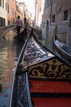 The bow of a gondola approaching a bridge across a busy canal in the San Marco district