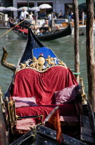 Empty moored gondola on the Grand Canal beside the Rialto Bridge with tourists passing in a gondola