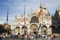 Tourists in the Piazza San Marco feeding pigeons in front of the Basilica of St Mark