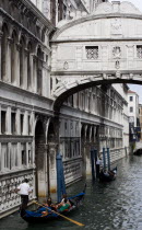 Gondolas with tourists passing on a canal beneath the Bridge of Sighs