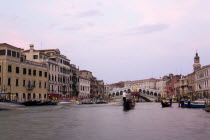 The Rialto Bridge at sunset spanning the Grand Canal busy with water traffic of gondolas and water taxis