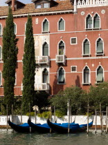 Gondolas moored at wooden posts in front of a Palazzo on the Grand Canal