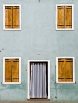 Green house with four shuttered windows on the lagoon island of Burano